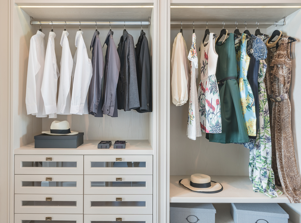 A minimalist wardrobe featuring neutral-colored blazers, denim, Dress, and a white shirt hanging on a clothing rack.